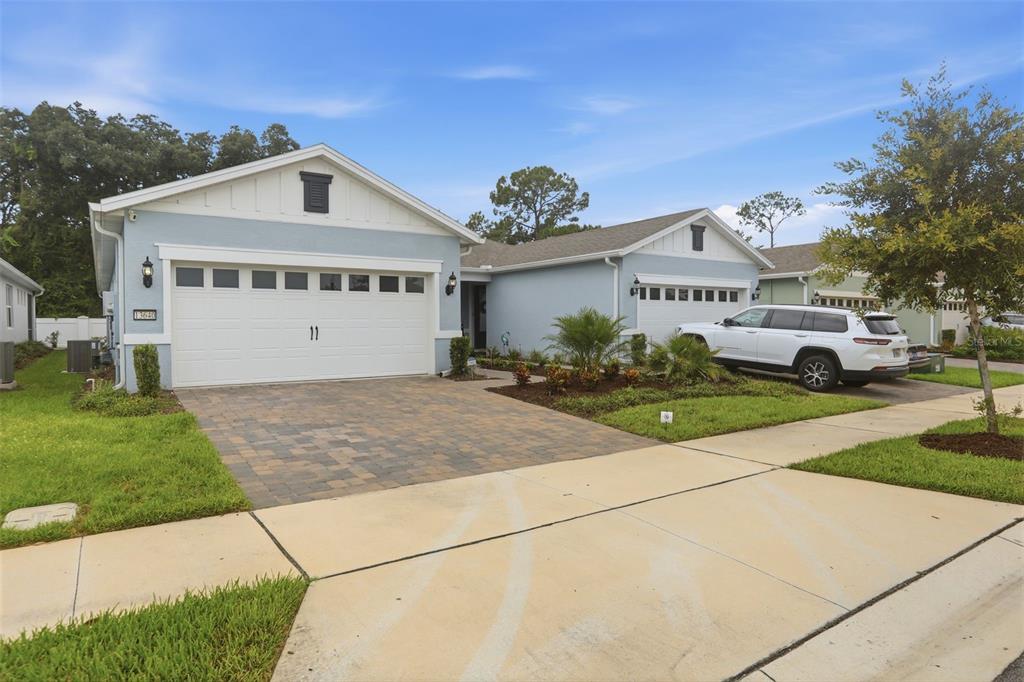 A light blue single-story house with a two-car garage and a paved driveway — 13640 SPLASHING ISLA DRIVE, WINTER GARDEN, FL