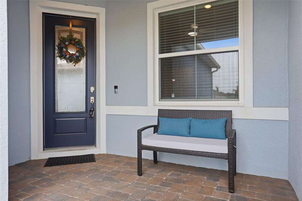 A front porch features a dark blue door, a window, and a wicker bench — 13640 SPLASHING ISLA DRIVE, WINTER GARDEN, FL