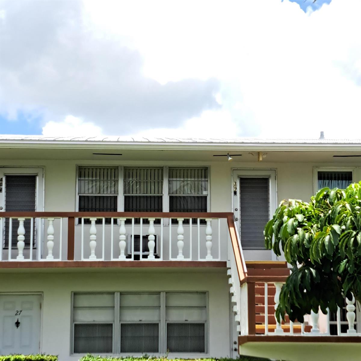 The exterior of a two-story apartment building features a wooden balcony with white railings — 39 Cambridge B, West Palm Beach FL 33417, WEST PALM BEACH, FL
