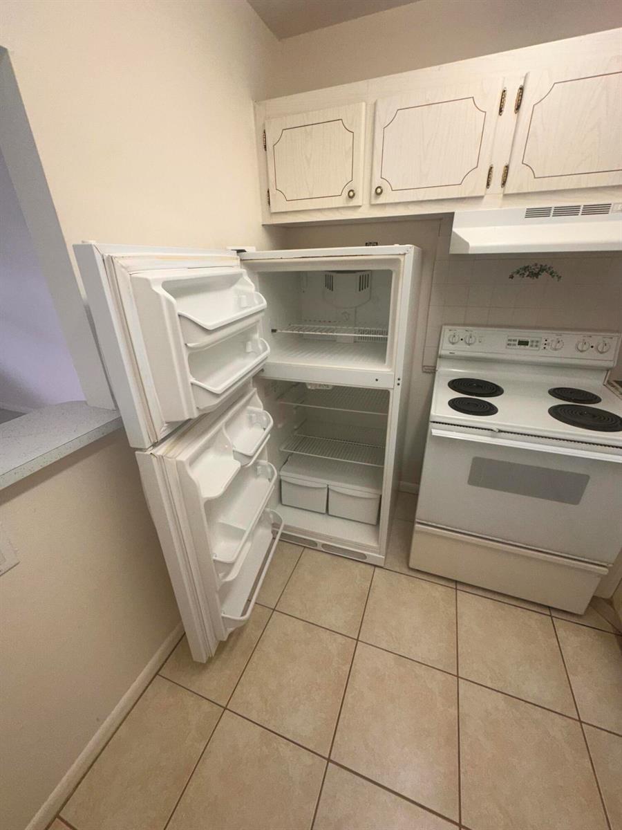 A kitchen features white cabinets, a white refrigerator with open doors, and a white stove — 39 Cambridge B, West Palm Beach FL 33417, WEST PALM BEACH, FL