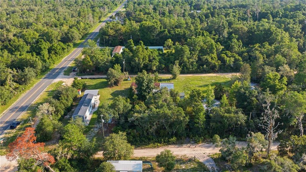 An aerial view shows a rural property with two houses, trees, and a paved road — TBD NE 235TH STREET, FORT MC COY, FL