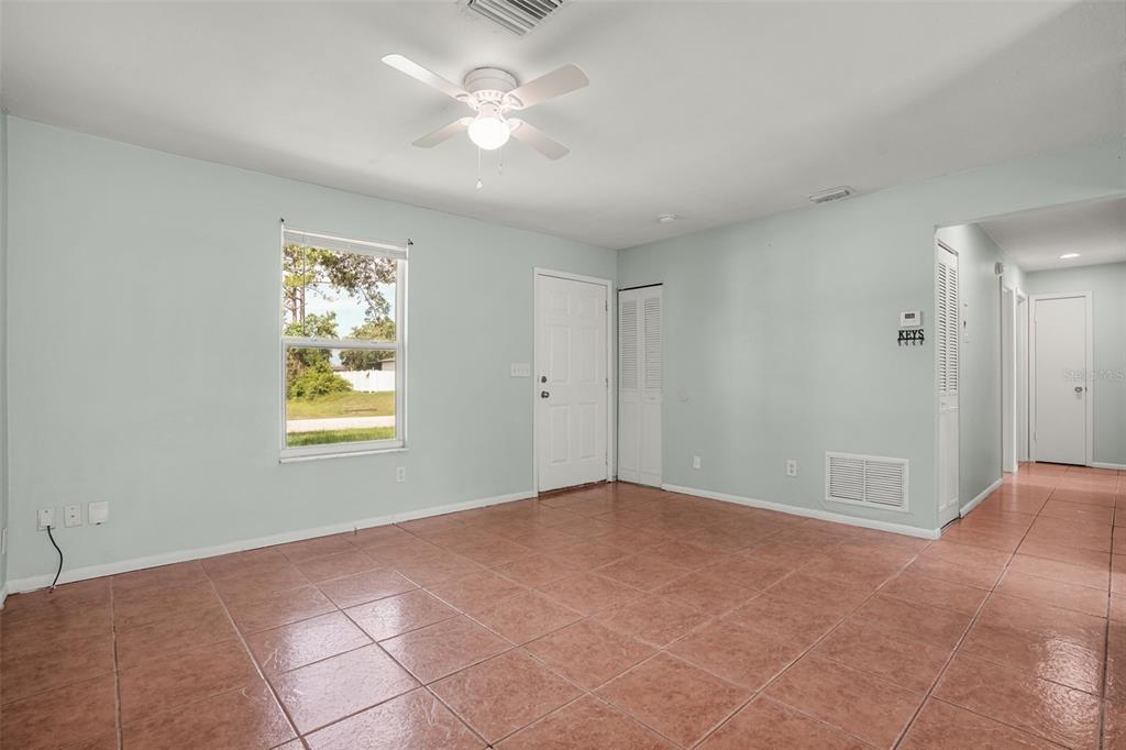 An empty room with light blue walls, tile flooring, a ceiling fan, and a window — 1067 LYRIC DRIVE, DELTONA, FL