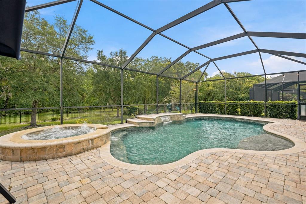 A screened-in patio features a paver deck, a swimming pool, and an elevated hot tub — 7929 HAMPTON LAKE DRIVE, TAMPA, FL