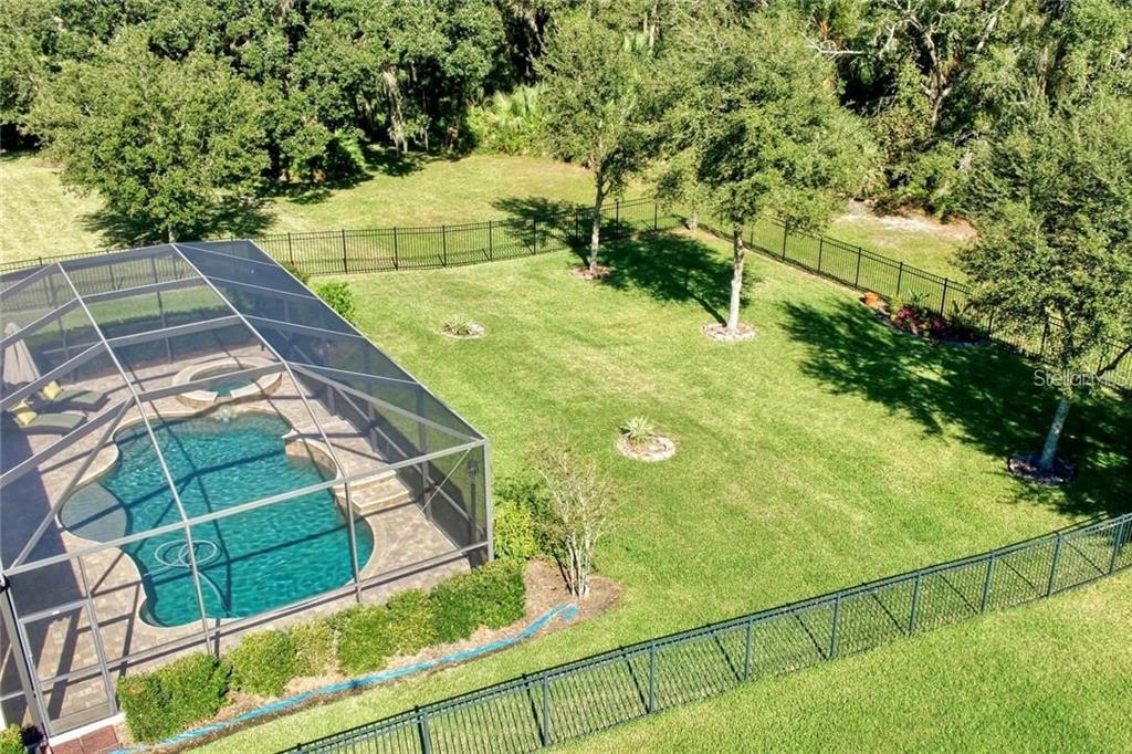 An aerial view of a backyard featuring a screened-in swimming pool and a fenced lawn — 7929 HAMPTON LAKE DRIVE, TAMPA, FL