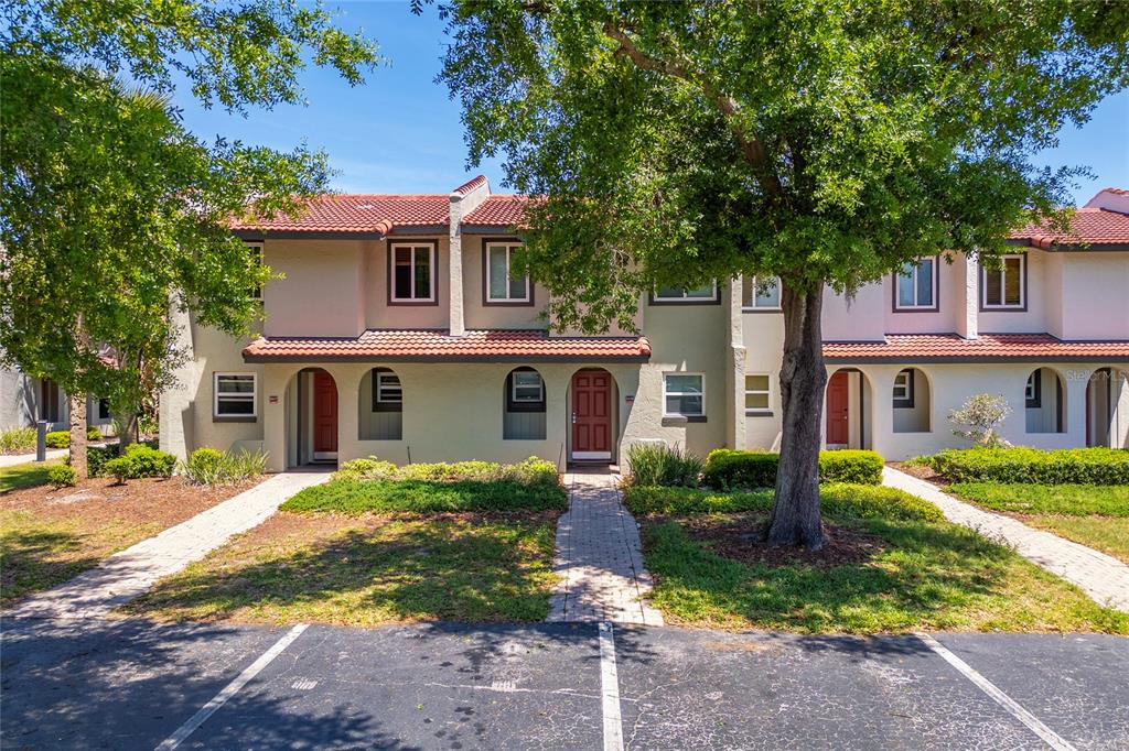 A row of two-story townhomes with beige stucco walls, red tile roofs, and paved walkways — 3118 MAGIC KINGDOM COURT, KISSIMMEE, FL