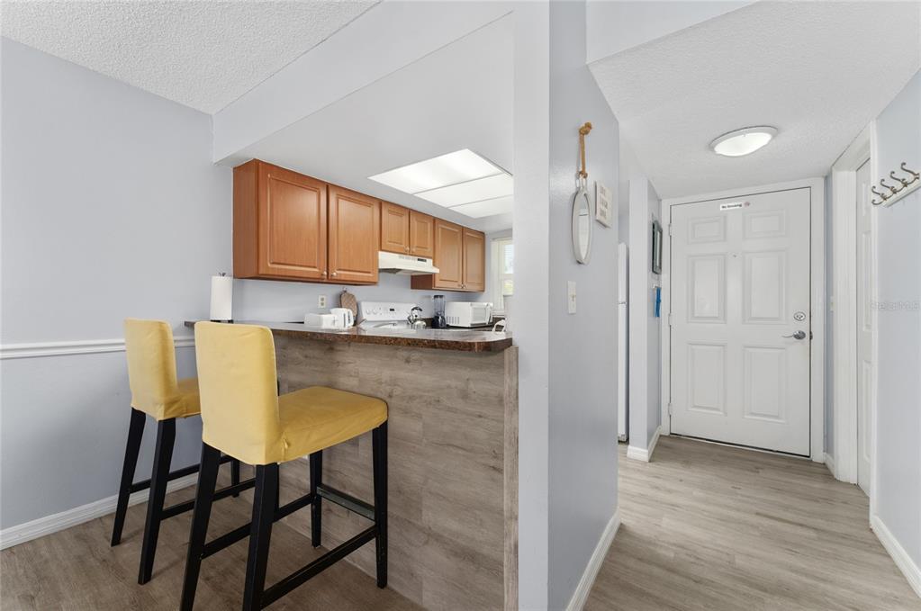 A kitchen with wood cabinets and a breakfast bar with two yellow chairs — 3118 MAGIC KINGDOM COURT, KISSIMMEE, FL