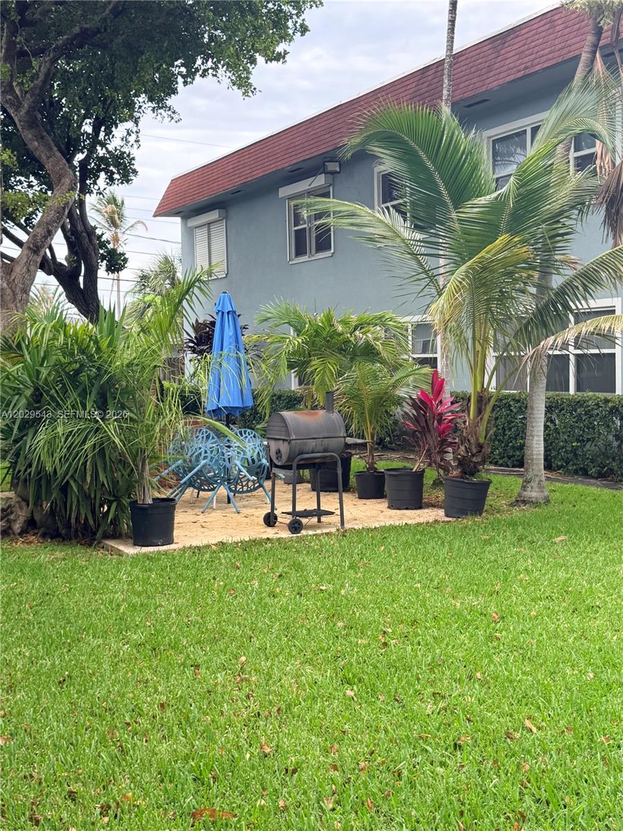 A patio area with a grill, outdoor furniture, and potted plants sits beside a building — 260 S Cypress Rd # 108, Pompano Beach FL 33060, POMPANO BEACH, FL