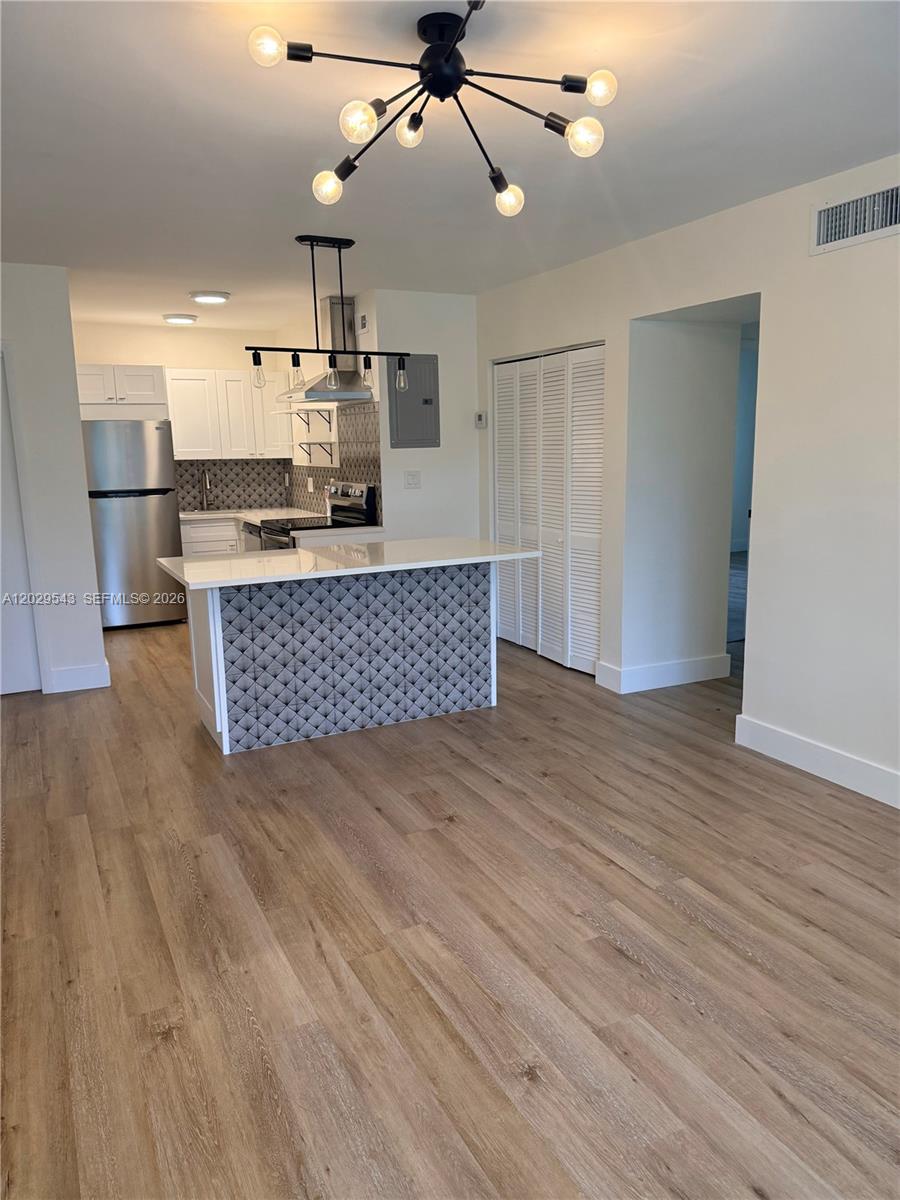 A kitchen features white cabinets, a patterned island, and a modern chandelier in an open space — 260 S Cypress Rd # 108, Pompano Beach FL 33060, POMPANO BEACH, FL