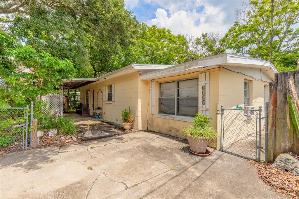 A single-story yellow house with a concrete driveway, a covered porch, and a chain-link fence — 1219 LEON LANE, DAYTONA BEACH, FL