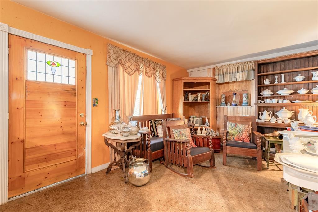 A room with orange walls, a wooden door, two wooden chairs, and a large hutch — 1219 LEON LANE, DAYTONA BEACH, FL