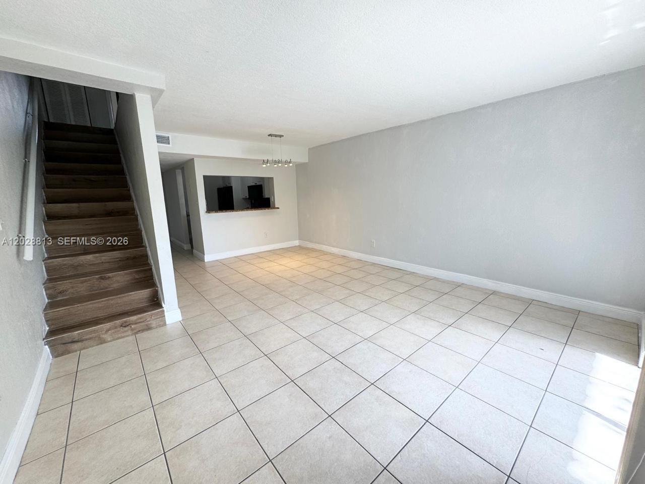 An open living area features light-colored tile flooring, a staircase, and a kitchen pass-through window — 8600 SW 109th Ave # 202, Miami FL 33173, MIAMI, FL