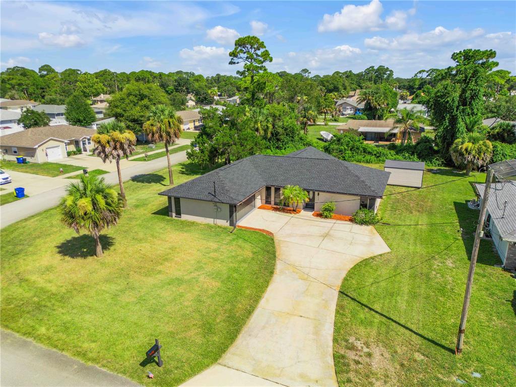 An aerial view shows a single-story house with a dark roof and a concrete driveway — 117 POINCIANA ROAD, EDGEWATER, FL