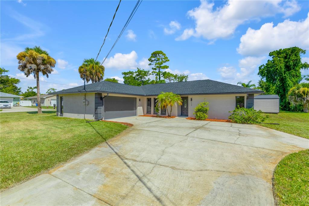 A single-story house with a gray garage, dark roof, and a concrete driveway — 117 POINCIANA ROAD, EDGEWATER, FL