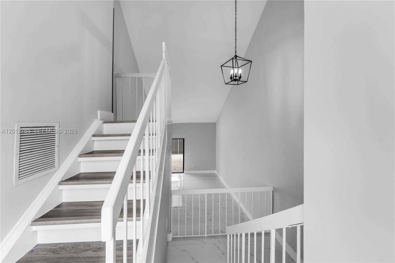 A staircase with wood-look treads and white railings leads to a landing with tile flooring — 6327 SW 127th Pl, Miami FL 33183, MIAMI, FL