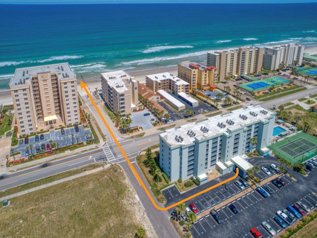 Aerial view of beachfront condominium buildings with an orange arrow indicating a path to the beach — 3800 S ATLANTIC AVENUE UNIT 702, DAYTONA BEACH SHORES, FL