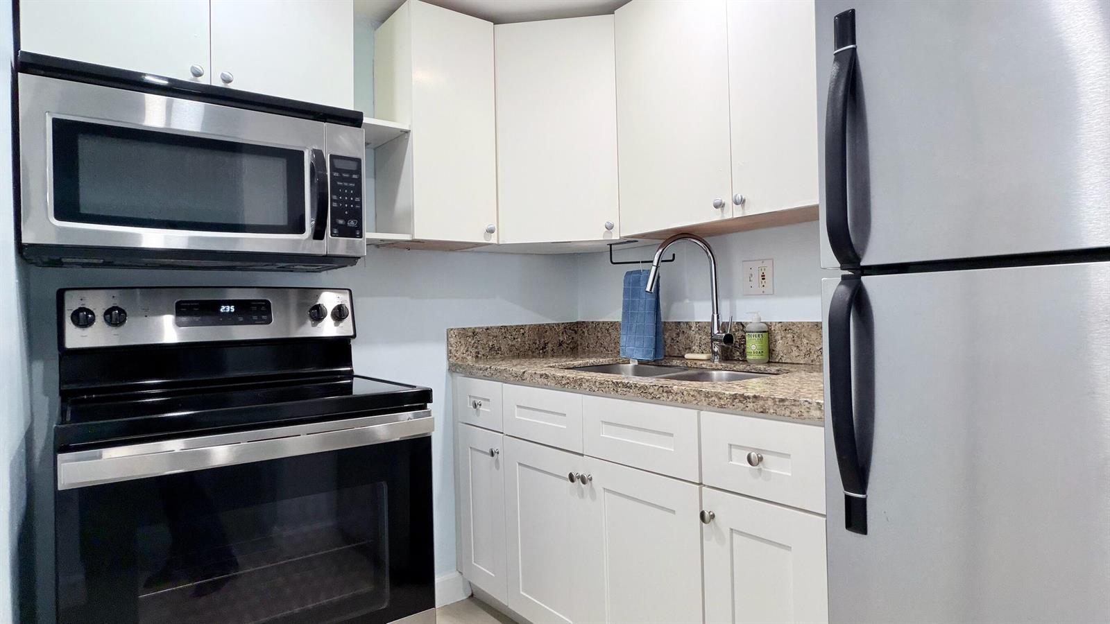 A kitchen features white cabinets, stainless steel appliances, and granite countertops — 251 SE 6th Avenue # 7, Pompano Beach FL 33060, POMPANO BEACH, FL