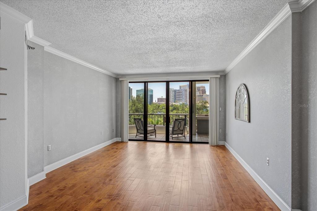An empty living room with wood flooring, gray walls, and a balcony overlooking city buildings — 401 E ROBINSON STREET UNIT 304, ORLANDO, FL