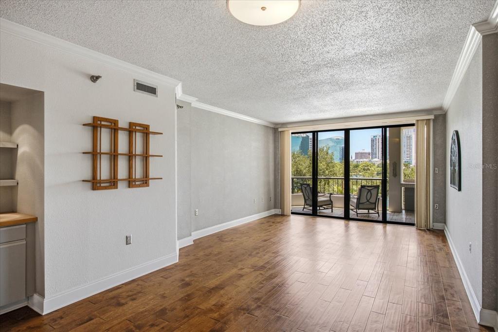 A living room with wood-look flooring, a wall-mounted shelf, and a balcony with city views — 401 E ROBINSON STREET UNIT 304, ORLANDO, FL