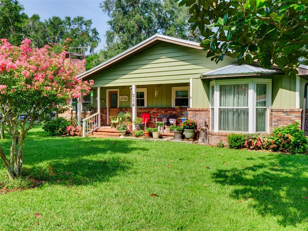 A single-story house with green siding, a brick foundation, and a front porch — 314 N YORK STREET, BUSHNELL, FL
