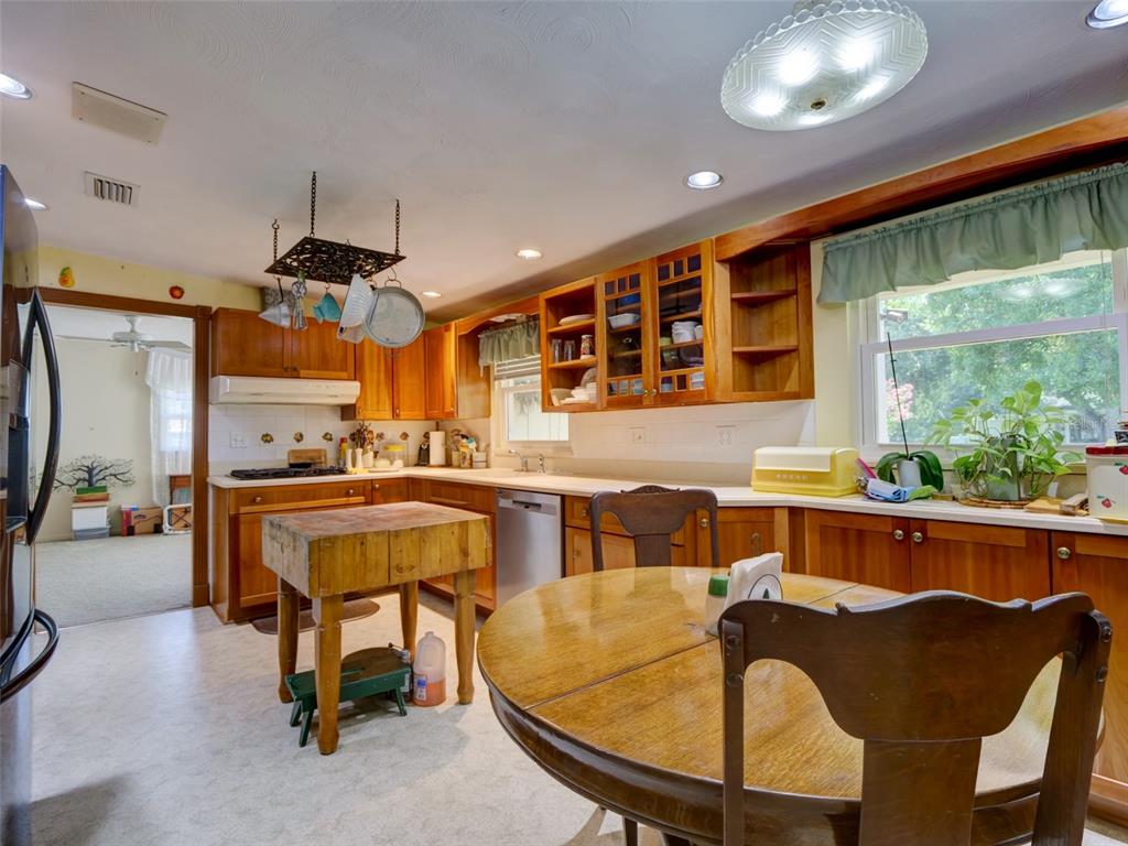 A kitchen with wood cabinets, a butcher block island, and a round wooden dining table — 314 N YORK STREET, BUSHNELL, FL