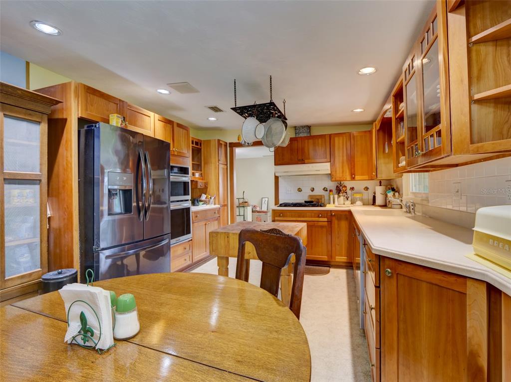 A kitchen features wood cabinetry, stainless steel appliances, a central island, and a round table — 314 N YORK STREET, BUSHNELL, FL