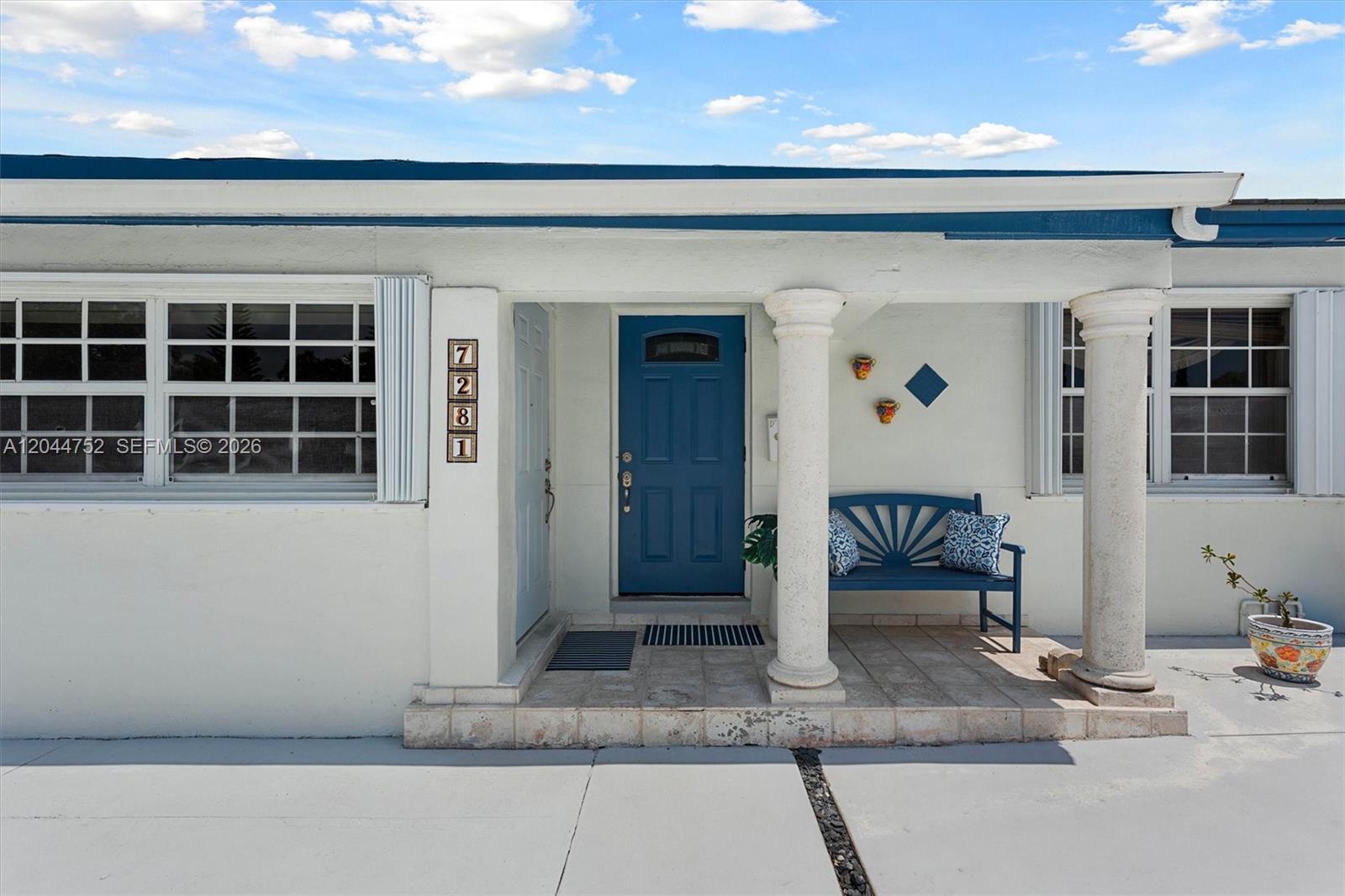 The exterior of a house features a blue front door, columns, and a matching bench — 7281 SW 13th Ter, Miami FL 33144, MIAMI, FL