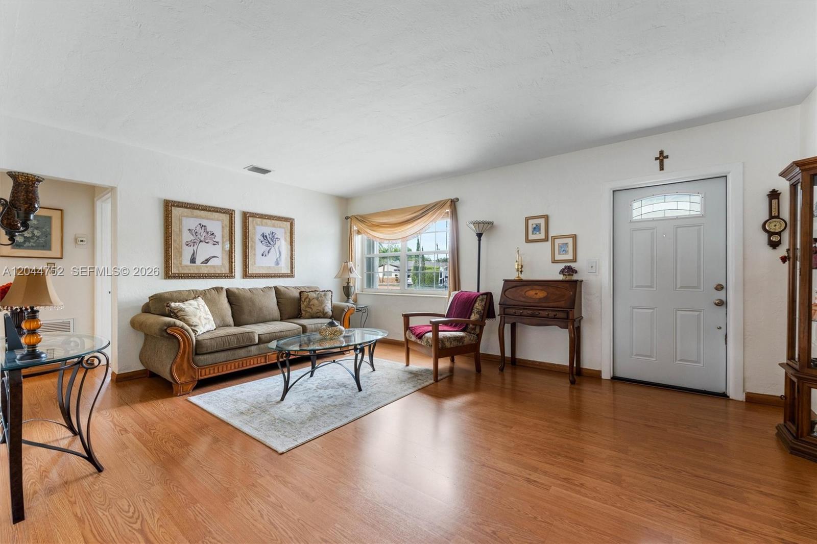 A living room features wood flooring, a beige sofa, a glass coffee table, and an entryway — 7281 SW 13th Ter, Miami FL 33144, MIAMI, FL