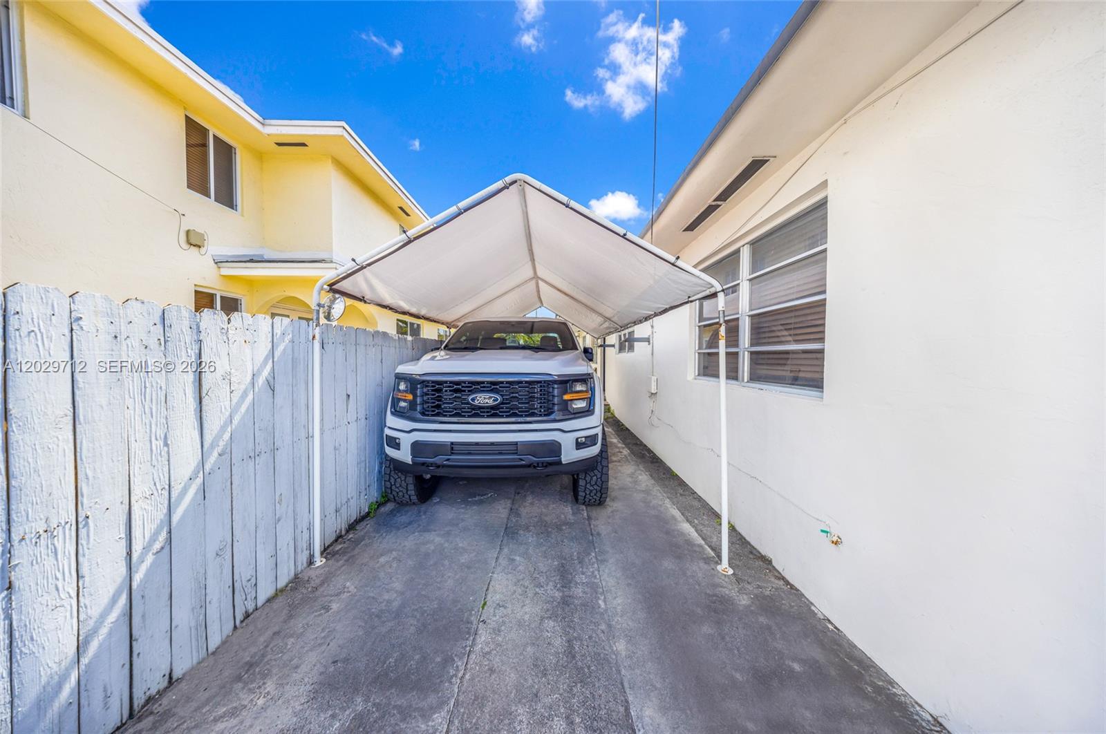 A white Ford pickup truck is parked under a canopy between a fence and building — 3532 NW 4th Ter, Miami FL 33125, MIAMI, FL