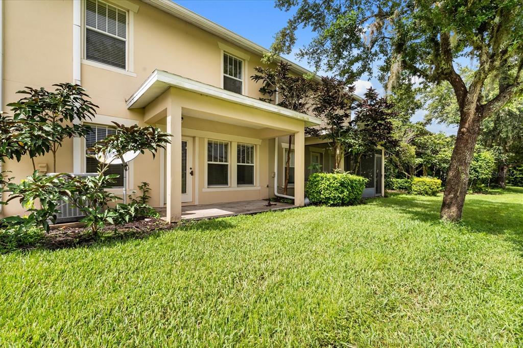 The exterior of a two-story house features a covered patio, lawn, and mature trees — 5454 CARAMELLA DRIVE, ORLANDO, FL