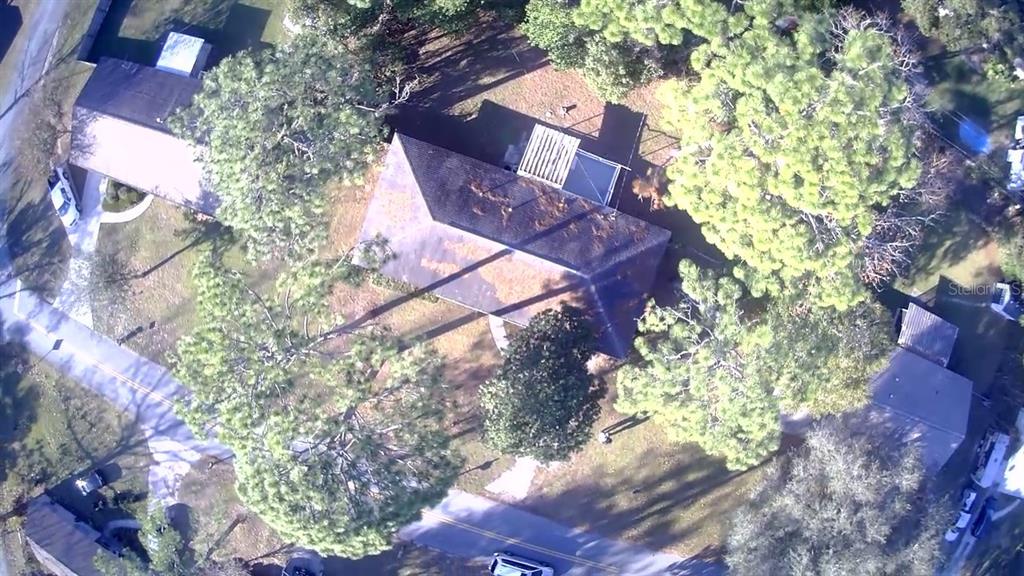 An aerial view shows a house with a dark roof surrounded by trees and driveways — 5701 SE 2ND PLACE, OCALA, FL