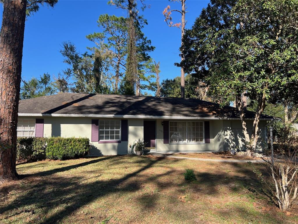 A single-story house with a gray roof, light-colored siding, and purple shutters — 5701 SE 2ND PLACE, OCALA, FL
