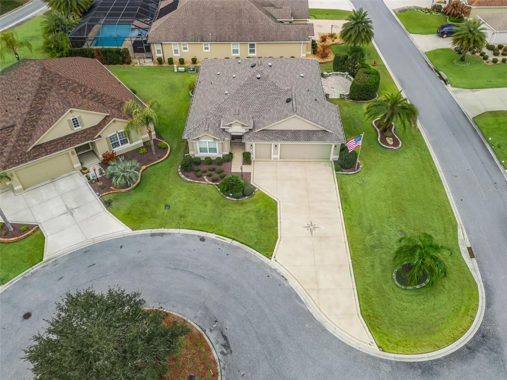An aerial view shows a suburban house with a concrete driveway and a landscaped yard — 3556 MISTLETOE COURT, THE VILLAGES, FL