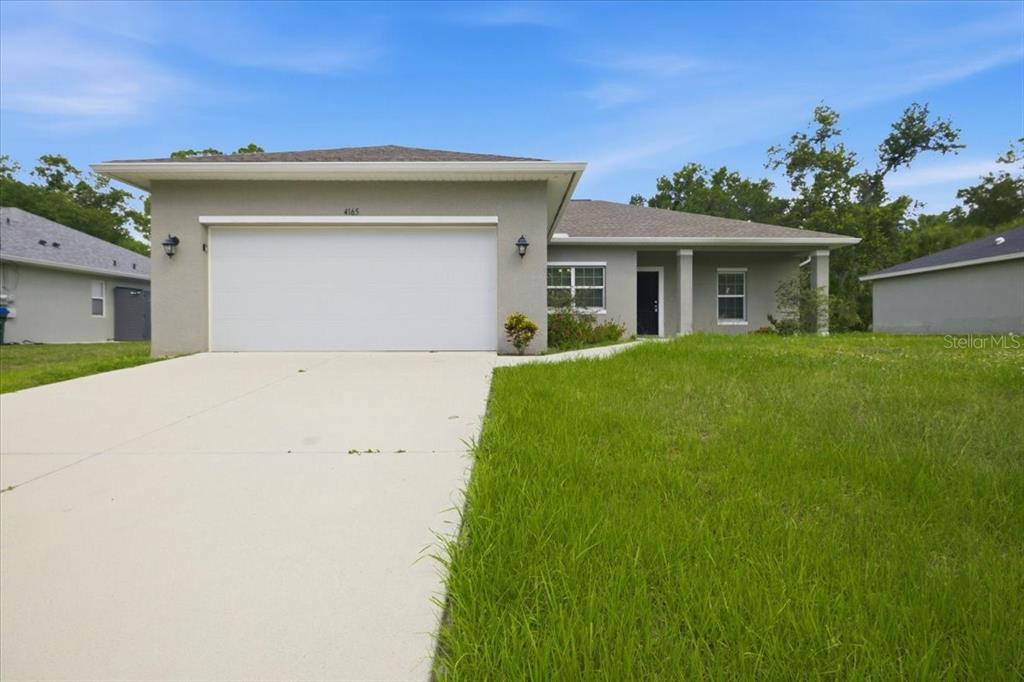 A single-story house with a two-car garage, gray stucco exterior, and a concrete driveway — 4165 TWINBUSH TERRACE, NORTH PORT, FL