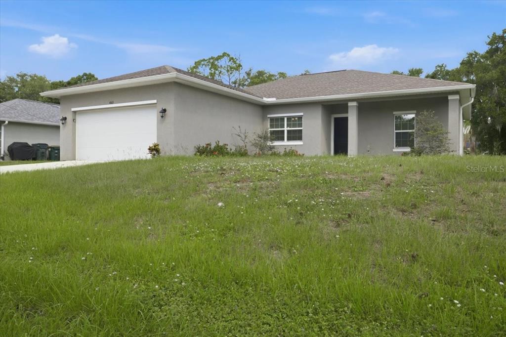 A single-story house with a gray stucco exterior, a two-car garage, and a grassy lawn — 4165 TWINBUSH TERRACE, NORTH PORT, FL