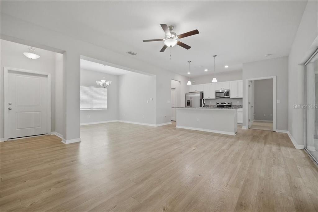 An open-concept living area features light wood-look flooring, a ceiling fan, and a kitchen — 4165 TWINBUSH TERRACE, NORTH PORT, FL