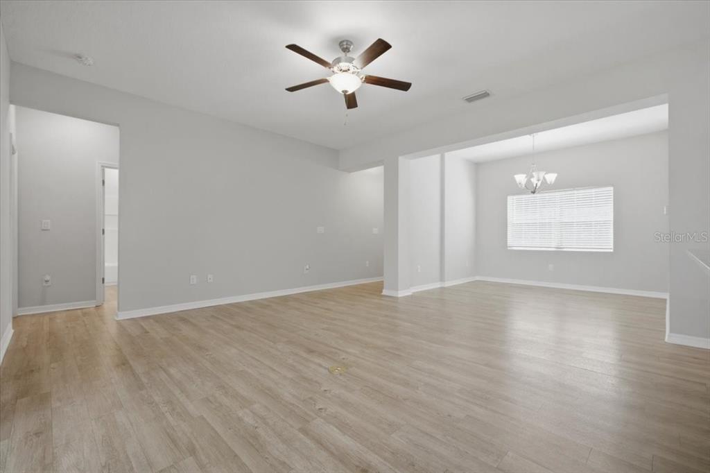 An empty living room features light wood-look flooring, gray walls, and a ceiling fan — 4165 TWINBUSH TERRACE, NORTH PORT, FL