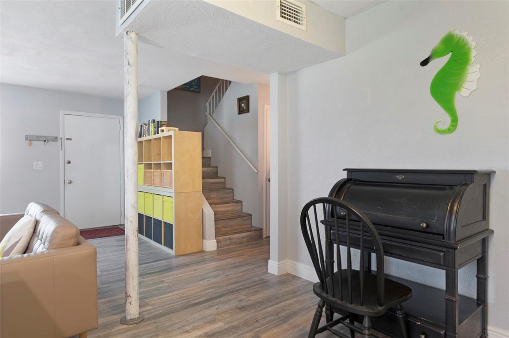 A living area features wood-look flooring, a staircase, a storage unit, and a roll-top desk — 3281 38TH WAY S UNIT C, ST PETERSBURG, FL