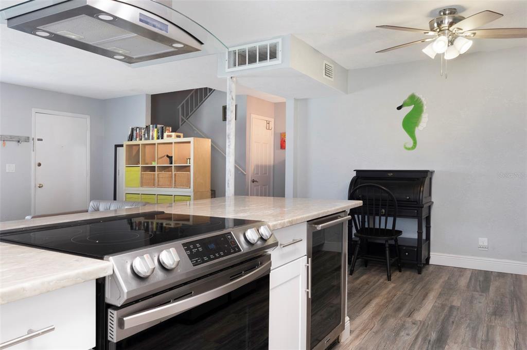 A kitchen island with a stainless steel stove faces a room with a seahorse wall decoration — 3281 38TH WAY S UNIT C, ST PETERSBURG, FL
