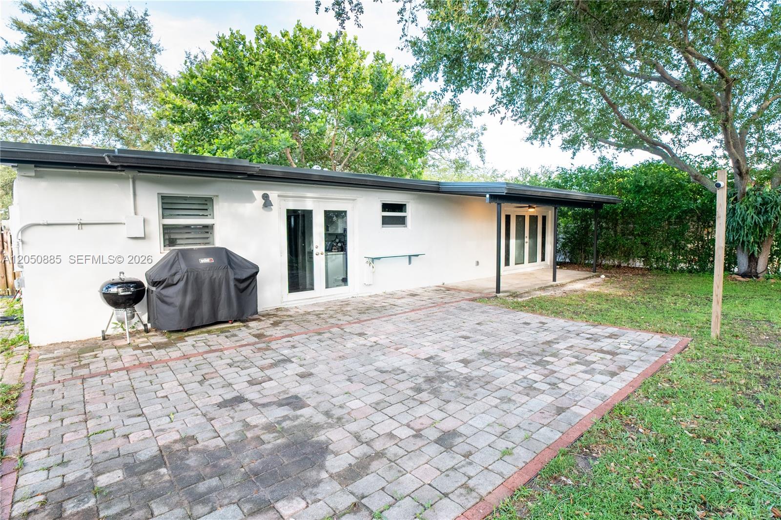 A paved patio sits outside a white house with a covered porch and grill — 5030 SW 113th Ct, Miami FL 33165, MIAMI, FL