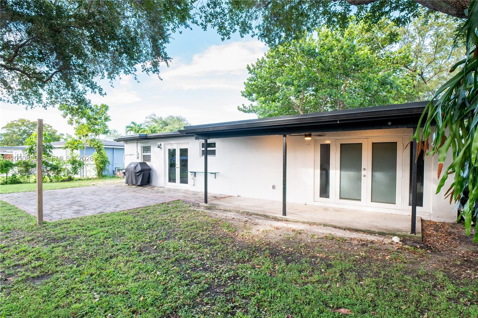 The exterior of a white house features a covered patio, brick pavers, and glass doors — 5030 SW 113th Ct, Miami FL 33165, MIAMI, FL