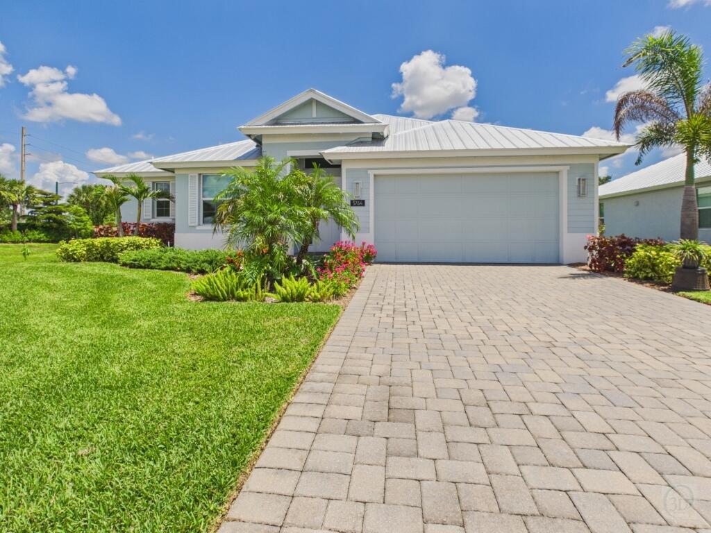 A light blue single-story house with a metal roof and a paved driveway — 5764 Arabella Lane, Vero Beach FL 32967, VERO BEACH, FL