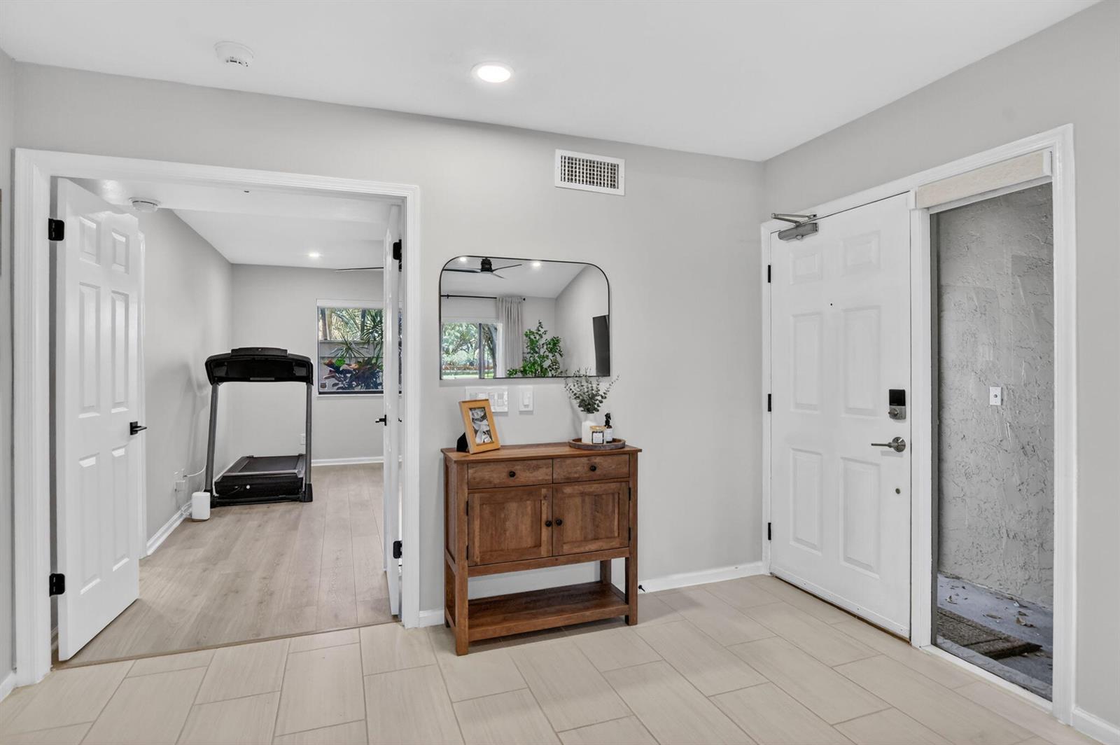 An entryway with tile flooring, a wooden console table, a mirror, and an adjacent room — 5530 Coach House Circle # A, Boca Raton FL 33486, BOCA RATON, FL
