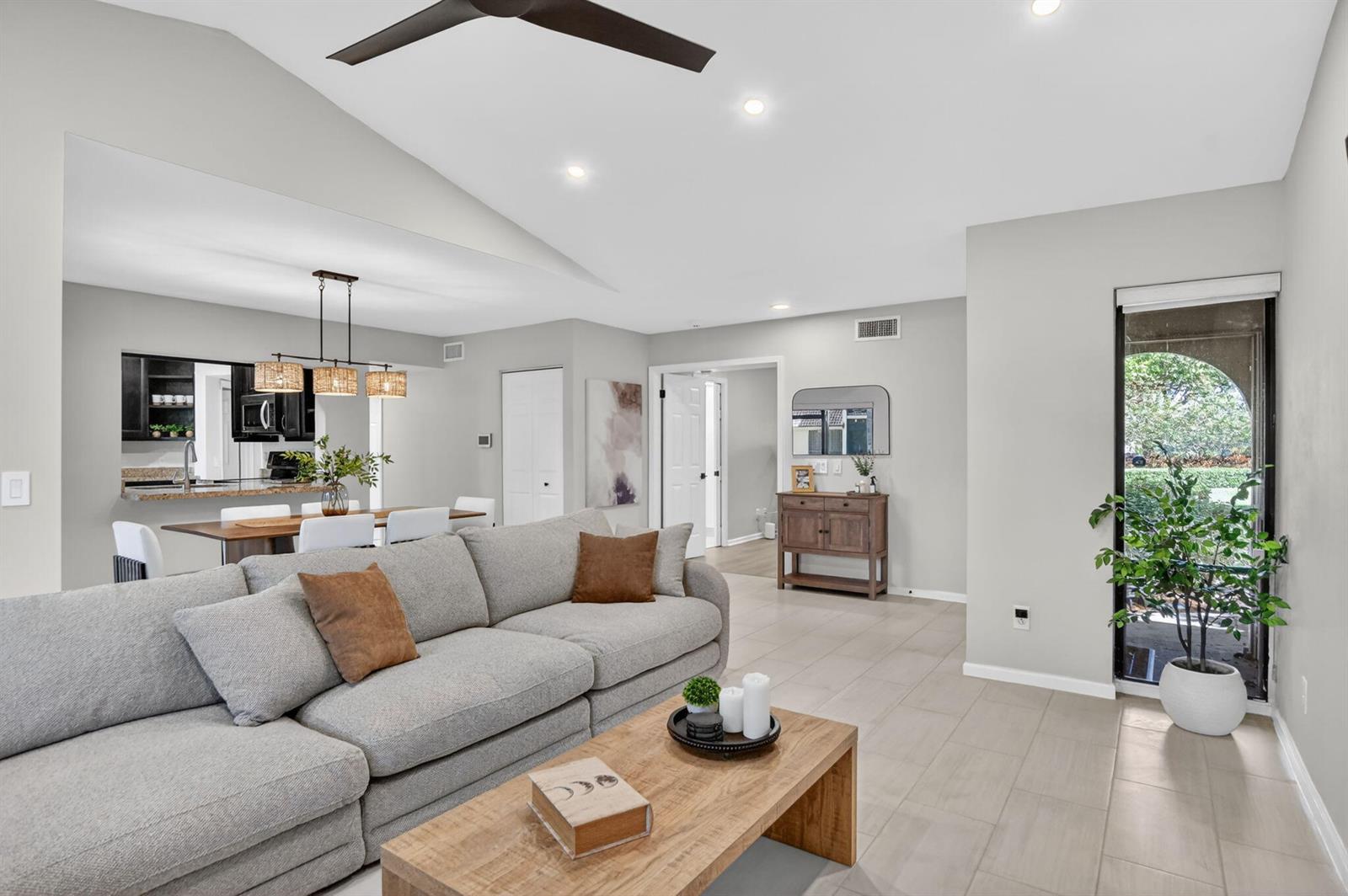 A living room with a gray sectional sofa, wood coffee table, and adjacent dining area — 5530 Coach House Circle # A, Boca Raton FL 33486, BOCA RATON, FL