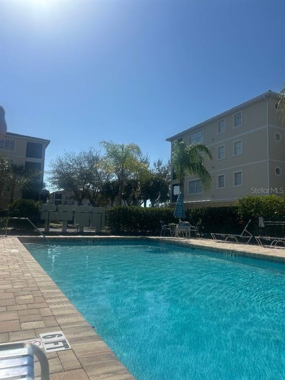 A rectangular swimming pool is surrounded by a stone deck and multi-story apartment buildings — 940 COOPER STREET UNIT 302, VENICE, FL
