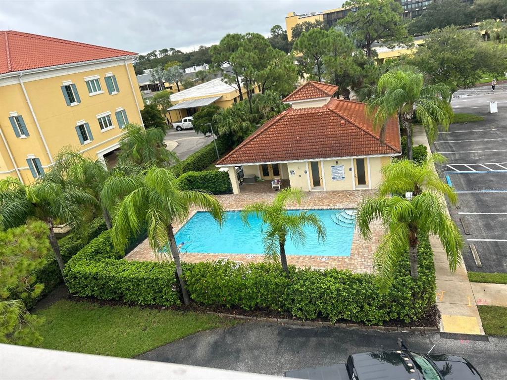An elevated view of a swimming pool and a small clubhouse with a tiled roof — 940 COOPER STREET UNIT 302, VENICE, FL