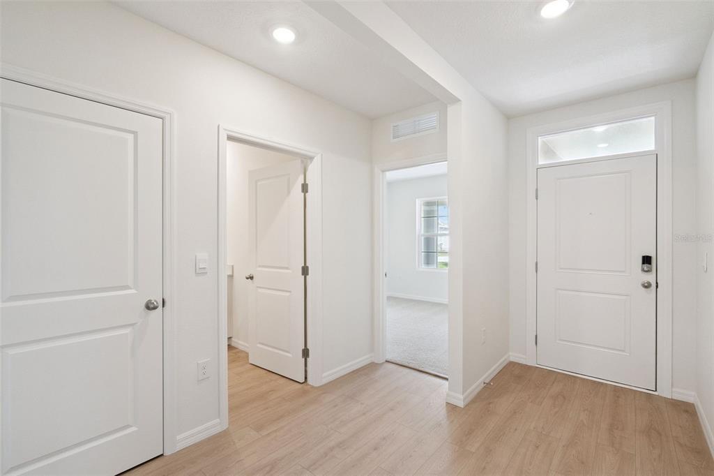 An entryway with light wood-look flooring, white walls, and several interior doors — 1168 MORFONTAINE STREET, DAYTONA BEACH, FL