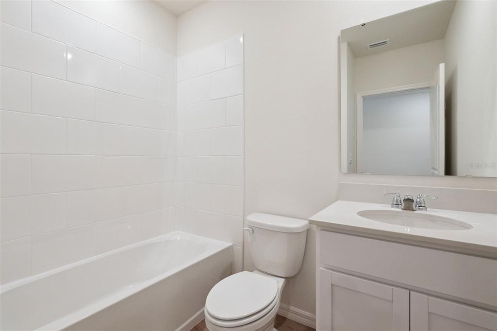 A bathroom features a white vanity, a toilet, and a bathtub with white subway tile — 1168 MORFONTAINE STREET, DAYTONA BEACH, FL