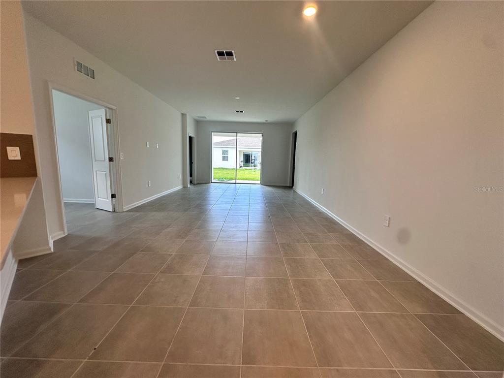 A covered entryway features a dark front door, a window with blue shutters, and concrete flooring — 5524 FIONA LANE, ST CLOUD, FL