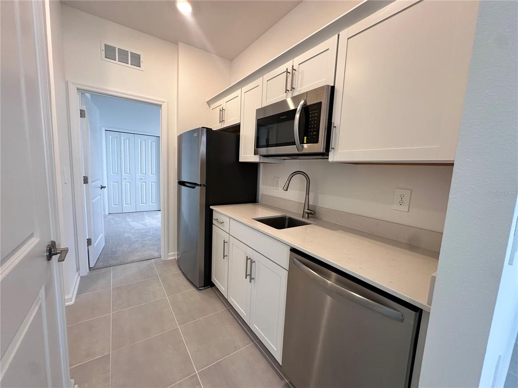 An empty room with large beige floor tiles, white walls, and a sliding glass door — 5524 FIONA LANE, ST CLOUD, FL