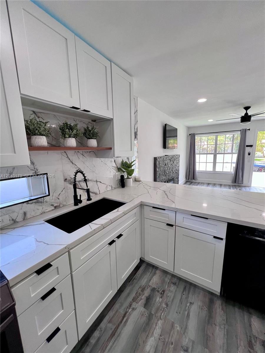 A kitchen features white cabinets, marble-patterned countertops, a black sink, and wood-look flooring — 2425 SW 26th Ln, Miami FL 33133, MIAMI, FL